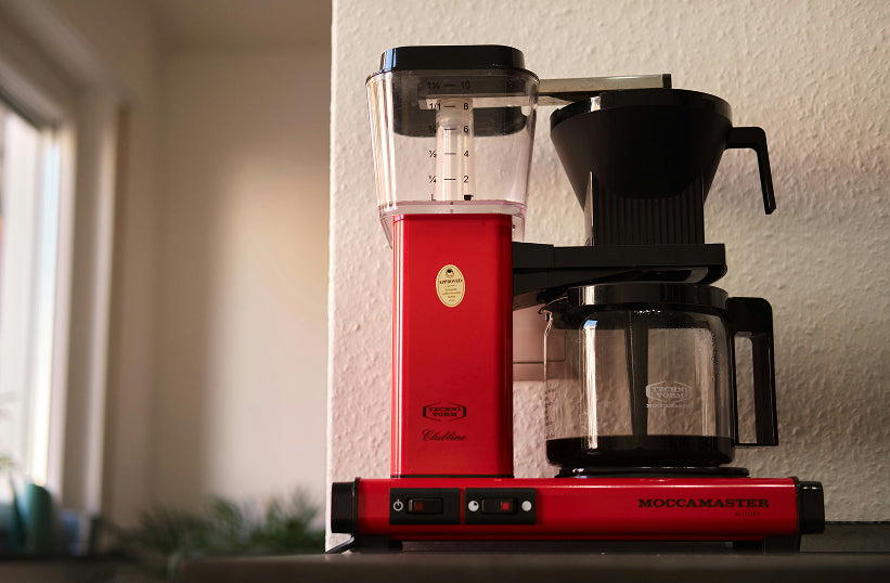 A red Moccamaster drip coffee maker on a kitchen counter