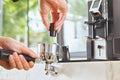 Two hands using a WDT distribution tool to stir grounds in a portafilter basket on an espresso setup