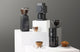 Baratza, Fellow Ode, and Eureka Peppe coffee grinders on white display blocks with coffee