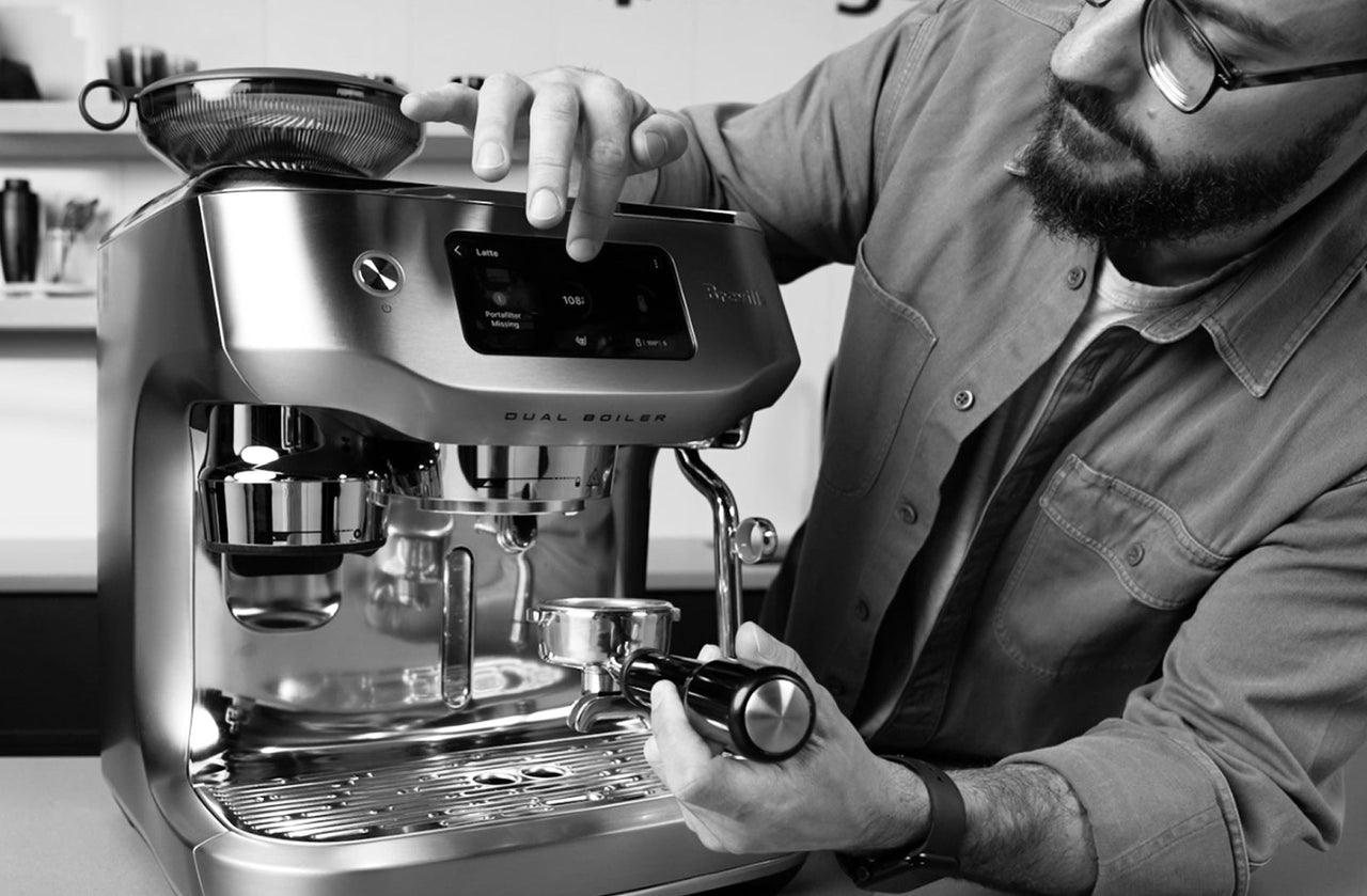 Barista adjusting a stainless steel Breville Dual Boiler espresso machine on a counter