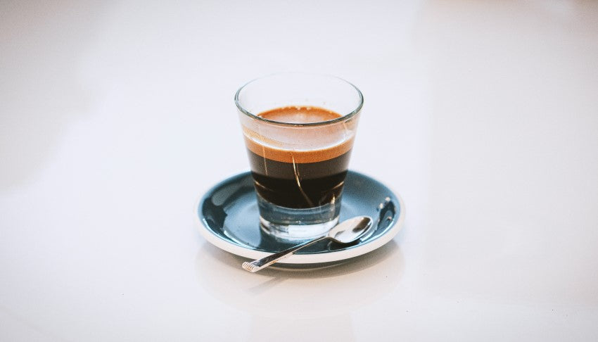 Espresso in a shot glass on a small plate - By Adi Goldstein for Unsplash