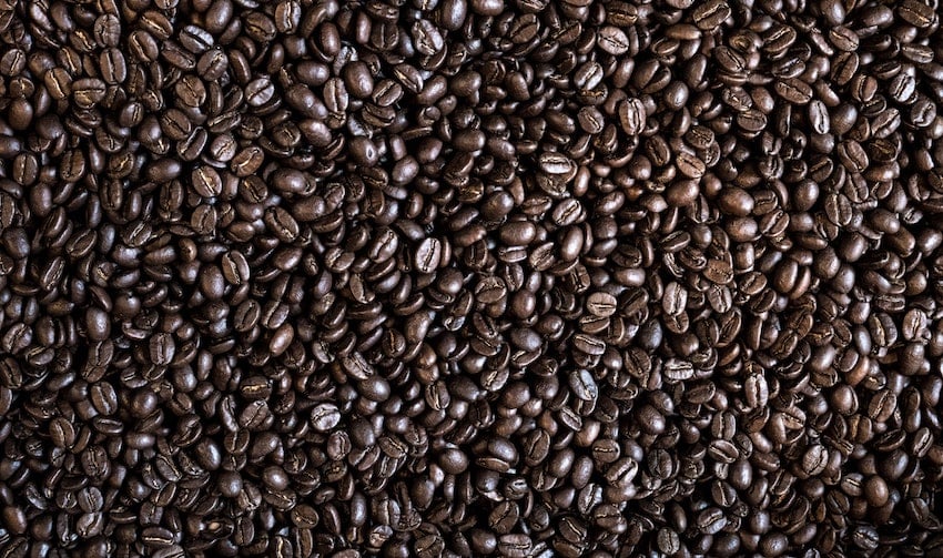 A scattered collection of whole roasted coffee beans photographed up close - Seattle Coffee Gear