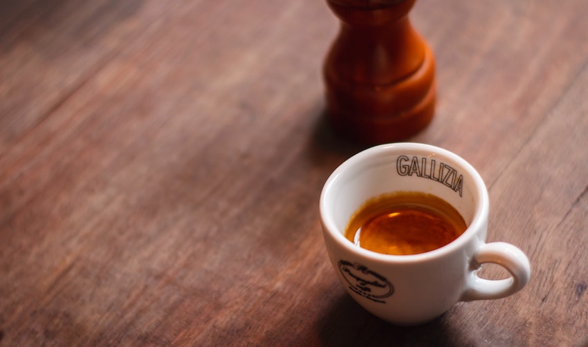 A cup of espresso on a table next to a coffee grinder - Seattle Coffee Gear