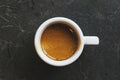 Overhead view of a coffee cup filled with a shot of espresso resting on a table surface
