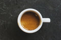 Overhead view of a coffee cup filled with a shot of espresso resting on a table surface