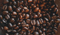 A close-up pile of roasted coffee beans spread across a dark background
