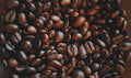 A close-up pile of roasted coffee beans spread across a dark background