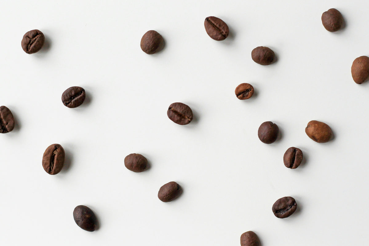 Coffee beans on a white backgroumd - by Nordwood Themes via Unsplash